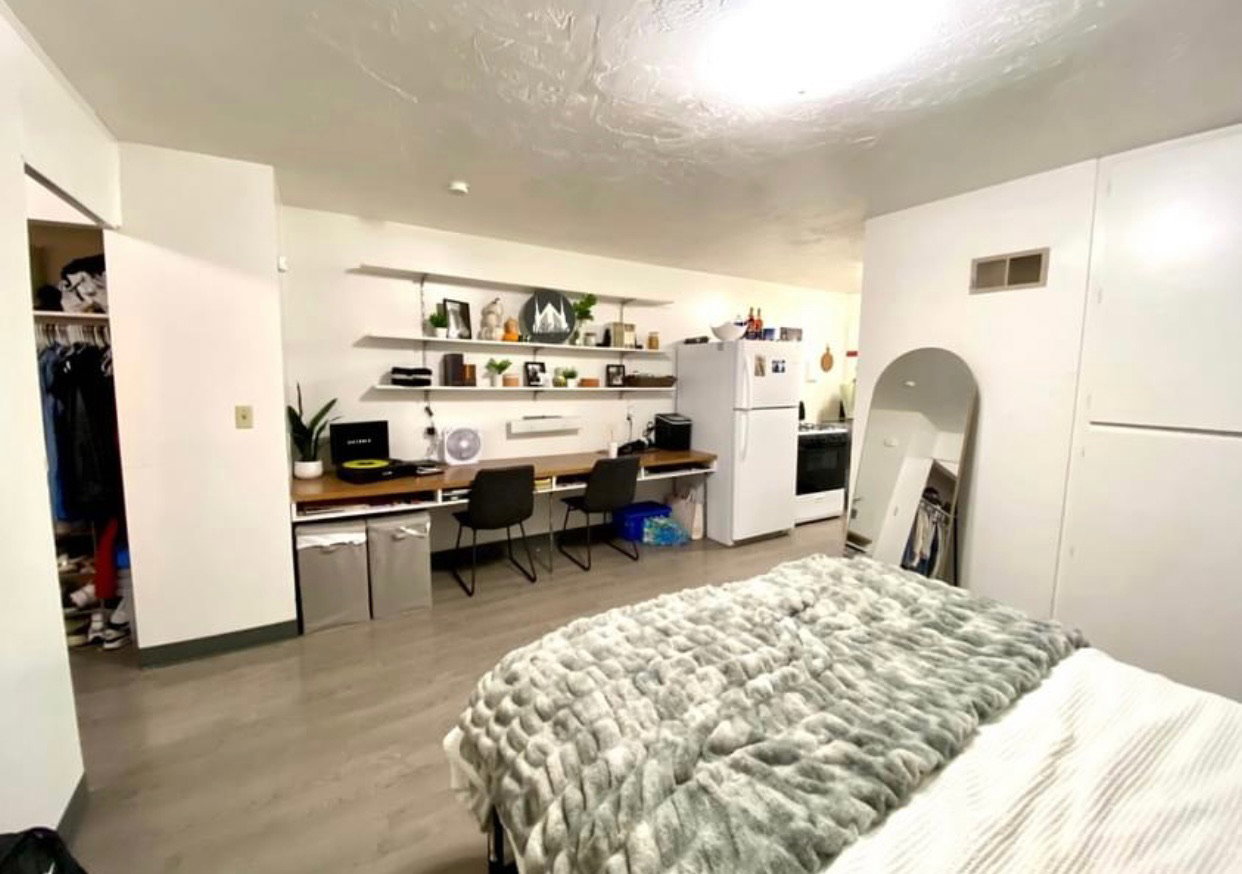 Bedroom featuring built in study area, freestanding refrigerator, light wood-style floors, a closet, and a textured ceiling