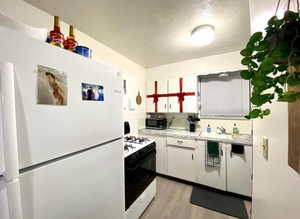 Kitchen featuring white appliances, light countertops, white cabinetry, backsplash, and light wood finished floors