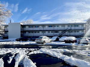 Snow covered building with a view of apartment building / complex and uncovered parking