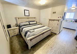 Bedroom featuring wood finished floors, a closet, and a textured ceiling