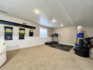 Workout room with carpet floors and a textured ceiling