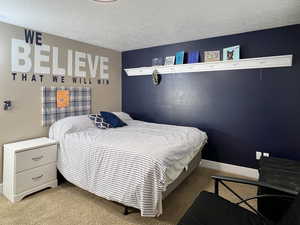 Bedroom with light carpet and a textured ceiling