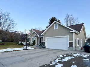 Craftsman inspired home with stucco siding, driveway, an attached garage, and roof with shingles