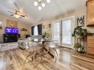 Dining area featuring ceiling fan, vaulted ceiling, french doors, and light wood-style floors