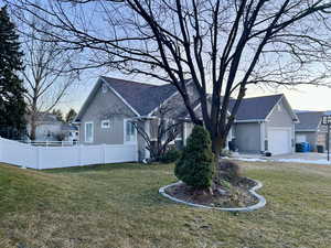 View of side of property featuring stucco siding, a shingled roof, and a garage