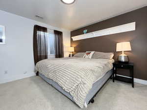 Bedroom with a textured ceiling and light colored carpet