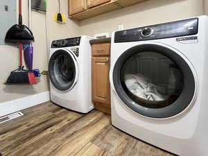 Laundry area featuring light wood-type flooring, cabinet space, and separate washer and dryer