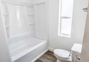 Bathroom featuring dark wood-style floors, shower / washtub combination, and healthy amount of natural light