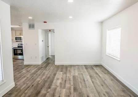 Unfurnished living room featuring dark wood finished floors and recessed lighting