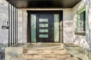 View of exterior entry with brick siding and a patio area