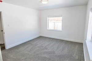 Carpeted empty room featuring baseboards