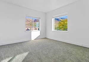 Spare room featuring carpet flooring and baseboards