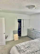 Bedroom featuring a textured ceiling and light colored carpet