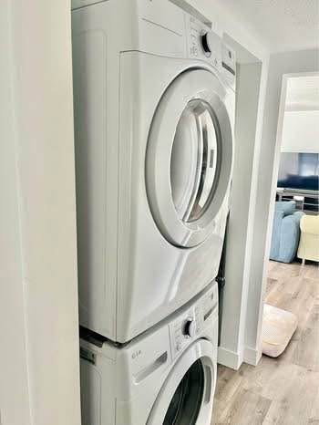 Laundry area with light wood-style floors and stacked washer / dryer