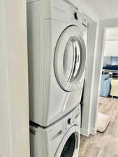 Laundry area with light wood-style floors and stacked washer / dryer