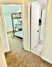 Corridor featuring light colored carpet and baseboards