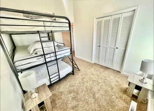 Bedroom with light colored carpet and a closet