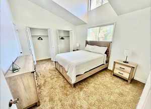 Bedroom with multiple closets, carpet flooring, and vaulted ceiling
