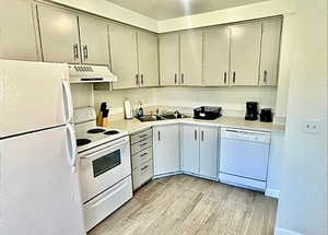 Kitchen with white appliances, wood tiled floors, gray cabinetry, and light countertops