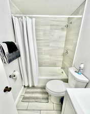 Bathroom featuring vanity, shower / bath combo with shower curtain, and light tile patterned floors