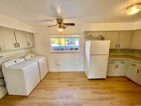 Laundry area featuring light wood-style floors, ceiling fan, and washing machine and clothes dryer