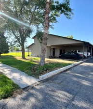 View of side of home featuring a lawn and a carport