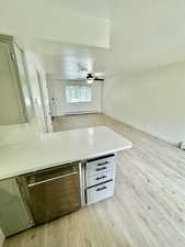 Kitchen featuring light wood-style flooring, open floor plan, a peninsula, a textured ceiling, and a baseboard heating unit