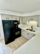 Kitchen featuring black appliances, light countertops, light wood finished floors, and a textured ceiling