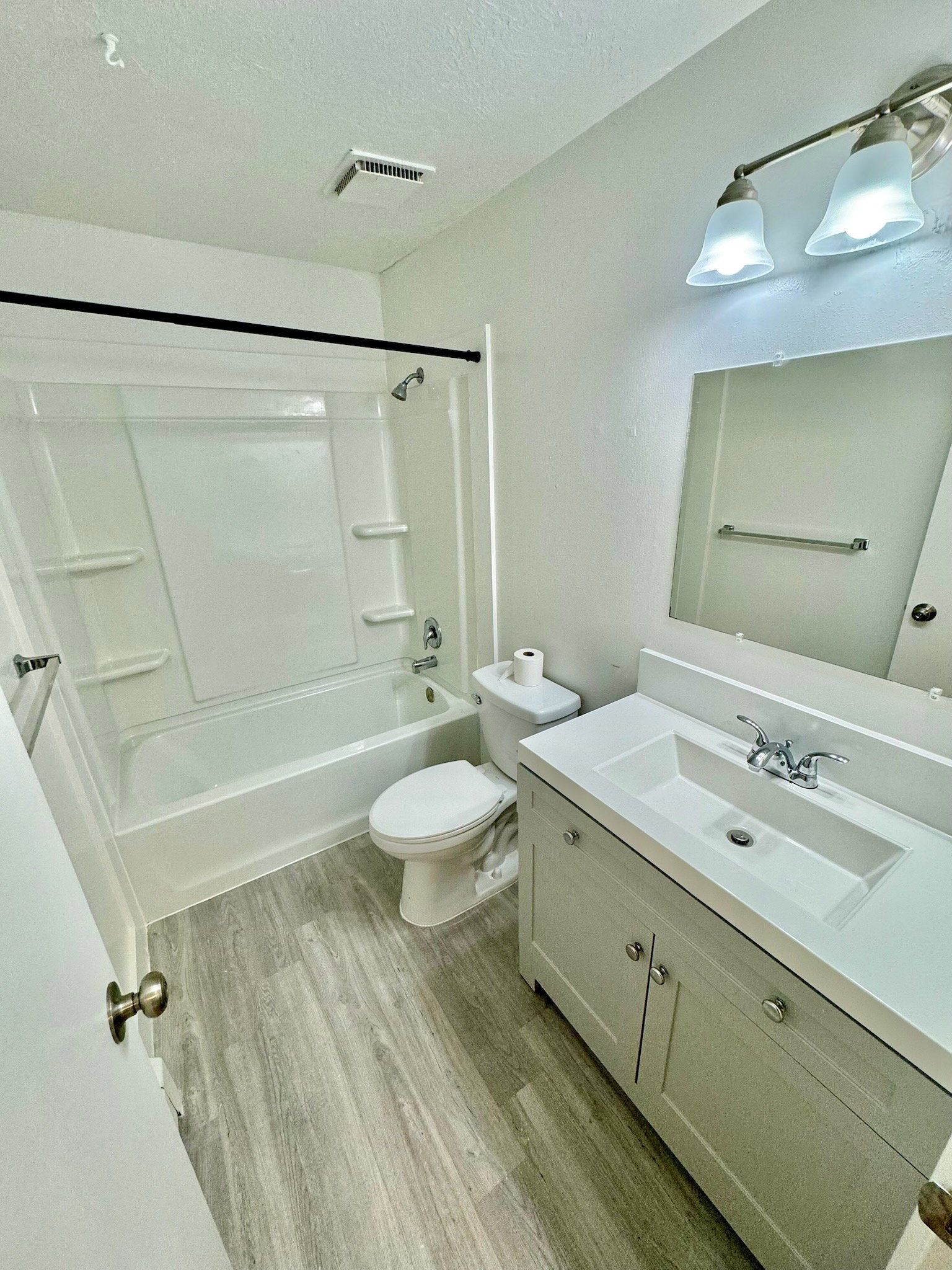 Full bathroom featuring vanity, shower / bathtub combination, light wood-type flooring, and a textured ceiling