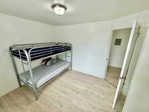 Bedroom featuring light wood-style floors, a textured ceiling, and electric panel