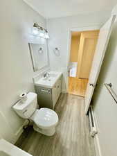 Half bath featuring vanity, light wood-type flooring, and a baseboard heating unit