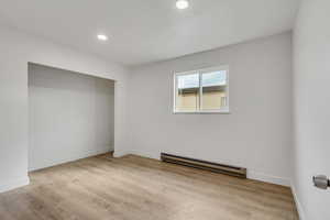 Unfurnished bedroom with a baseboard radiator, light wood-type flooring, and recessed lighting