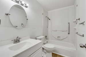 Full bathroom featuring vanity, tile walls, bathtub / shower combination, wainscoting, and light wood finished floors