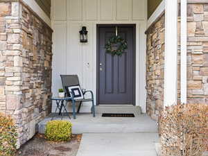 Property entrance featuring stone siding and covered porch
