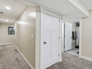 Corridor with neutral colored carpet and recessed lighting