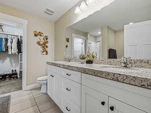 Ensuite bathroom featuring a walk in closet, double vanity, a shower stall, garden tub, granite countertop and light tile floors