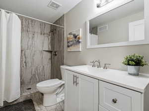 Full bathroom with vanity, a shower stall, and upgraded shower surround
