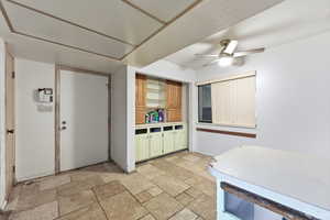 Kitchen featuring light countertops, a ceiling fan, and stone tile floors