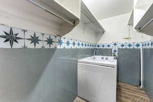 Laundry area featuring washer / clothes dryer, light wood finished floors, and tile walls