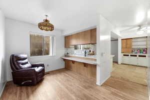 Kitchen featuring light countertops, a peninsula, a breakfast bar area, wood finish cabinets, and light wood-style floors