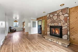 Unfurnished living room with wood finished floors and a stone fireplace