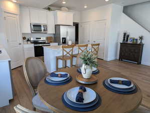 Kitchen featuring dark wood-type flooring, stainless steel appliances, white cabinets, recessed lighting, and a center island