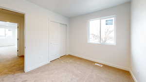 Unfurnished bedroom with light carpet and a closet