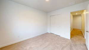 Unfurnished bedroom with light colored carpet, a closet, and recessed lighting
