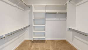 Walk in closet with light colored carpet