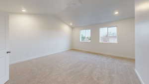Spacious, vaulted primary suite with vaulted ceiling, light carpet, and recessed lighting