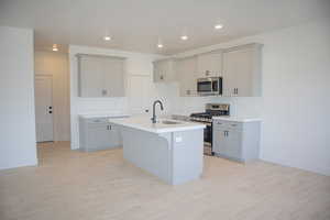 Kitchen with painted wood cabinets, quartz slab countertops, 42" uppers, gas range, dishwasher, microwave and disposal.