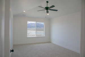 Primary bedroom with vaulted ceiling and ceiling fan.