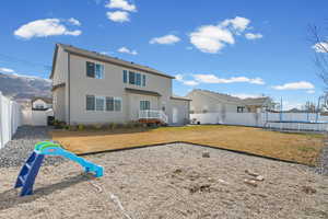 Back of house featuring a fenced backyard, stucco siding, a trampoline, and a mountain view