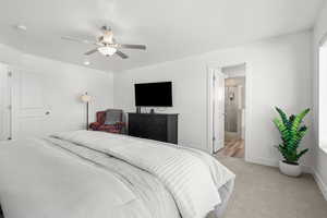 Bedroom with light colored carpet, ceiling fan, and ensuite bath